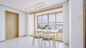 Una habitación con un ventanal grande, una puerta de madera y una mesa con sillas.