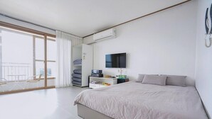 Un dormitorio de hotel moderno con una cama grande, un televisor de pantalla plana, un armario y un balcón con vistas.
