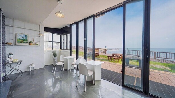 Una habitación moderna con ventanas amplias, una zona de cocina y vista a la playa.