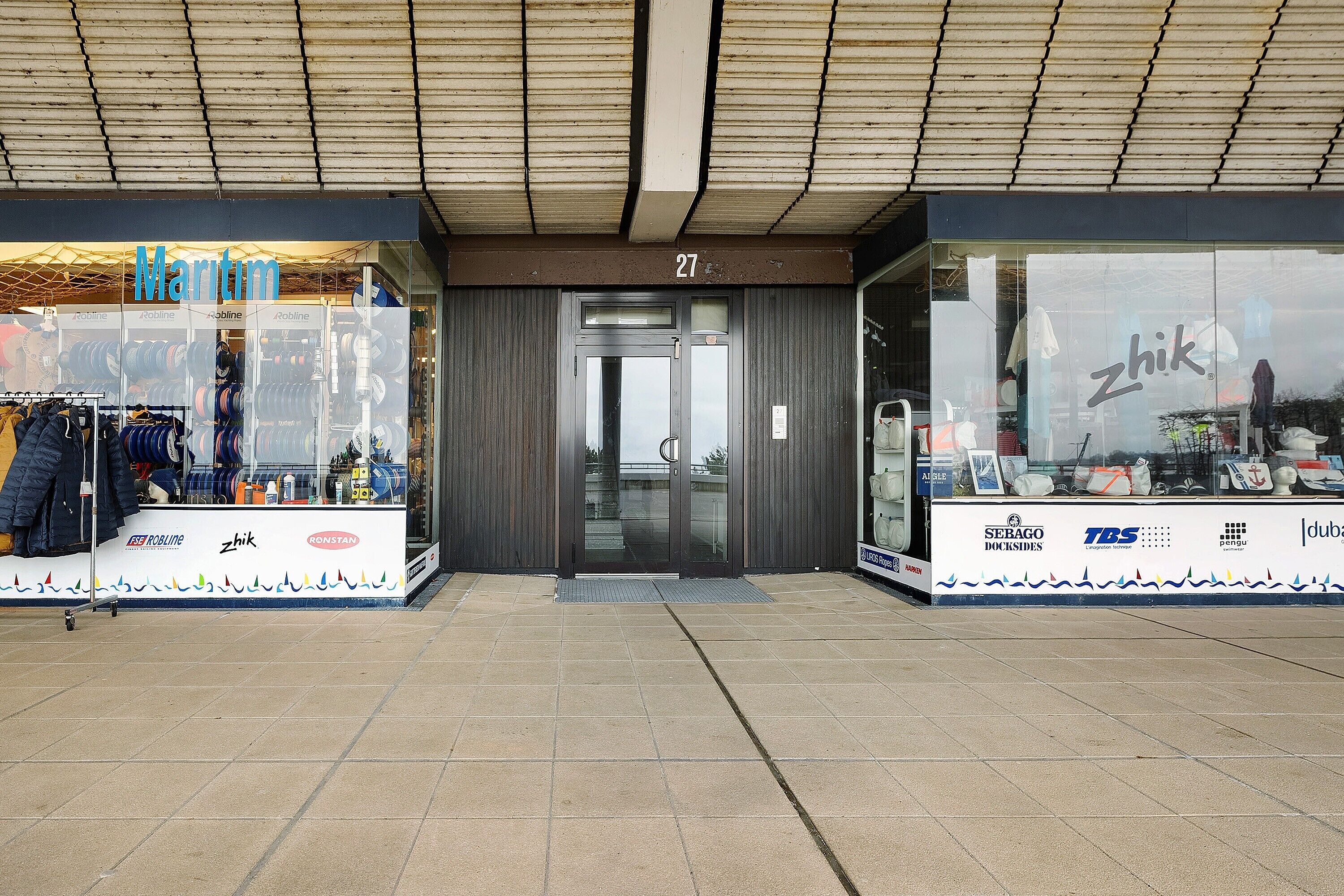 A storefront with the name 'Maritim' and 'zhik' visible, featuring a tiled entrance and a wooden ceiling.