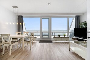 Ein modernes Zimmer mit Esstisch, Stühlen, Fernseher und großem Fenster mit Aussicht.