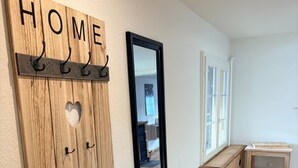 Ein an der Wand befestigter, hölzerner Garderobenständer mit Haken und Spiegel.