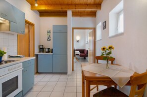 Una cocina con estufa, horno y armarios azules, que da paso a un comedor con mesa y sillas.
