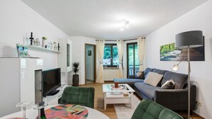 A modern living room with a sofa, green chairs, a coffee table, a TV, and a lamp.