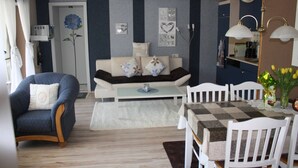 A living room with a sofa, armchairs, a coffee table, and a dining table with chairs.