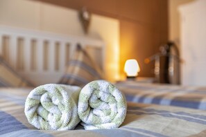 Ein Bett mit zwei gerollten Handtüchern und einem Heizkörper im Hintergrund.