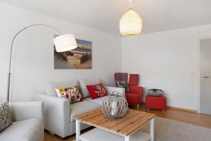 A modern living room with a sofa, armchairs, a coffee table, and a hanging light fixture.