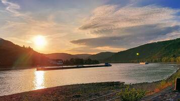 Un río con barcos, un puente y un paisaje montañoso al atardecer.