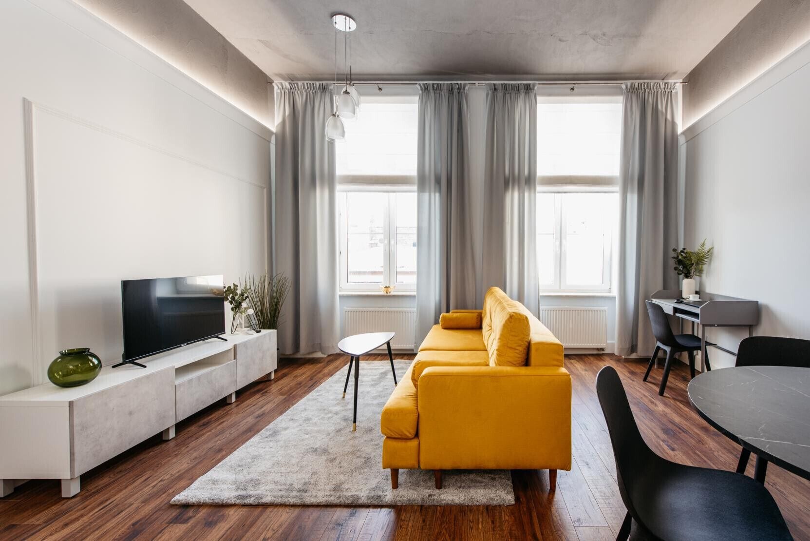 A modern living room with a sofa, TV, and dining area.