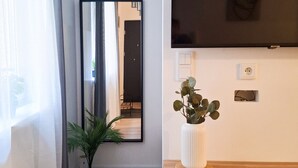A modern living room with a large flat-screen TV mounted on the wall, a potted plant, and a wooden coffee table. - Berka Joselewicza 12/30 (Kraków)