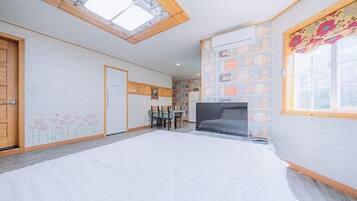 Un dormitorio con tragaluz, una cama, un televisor, una zona de comedor y una pared decorada con platos.
