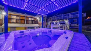 Un área de hidromasaje con un porche cubierto, una piscina y un edificio con balcón.