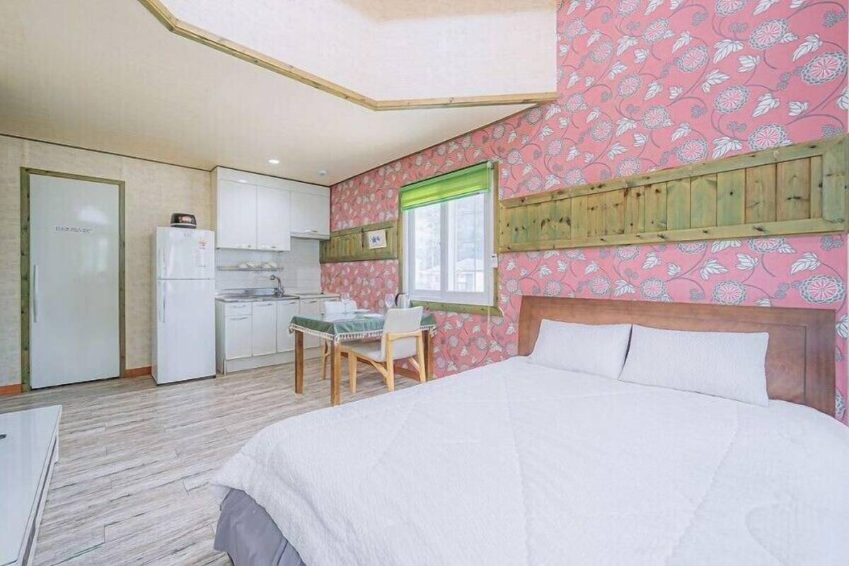 Una habitación compacta con cama, un pequeño kitchenette, una mesa de comedor y un televisor.