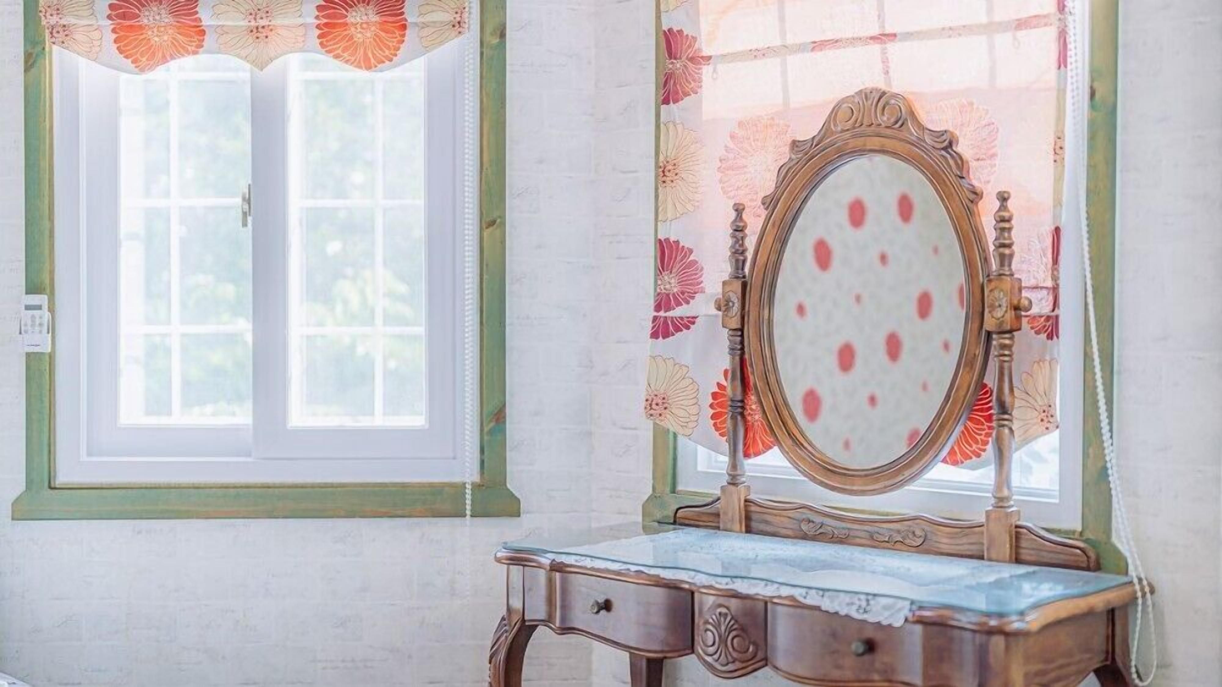A room with a window, a mirror, and a dresser.
