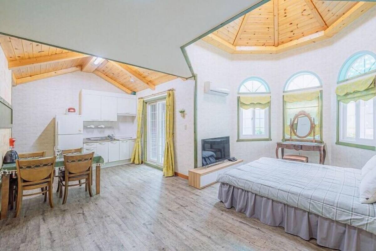 Un dormitorio con techo de madera, una cama, un televisor y un escritorio con una silla.