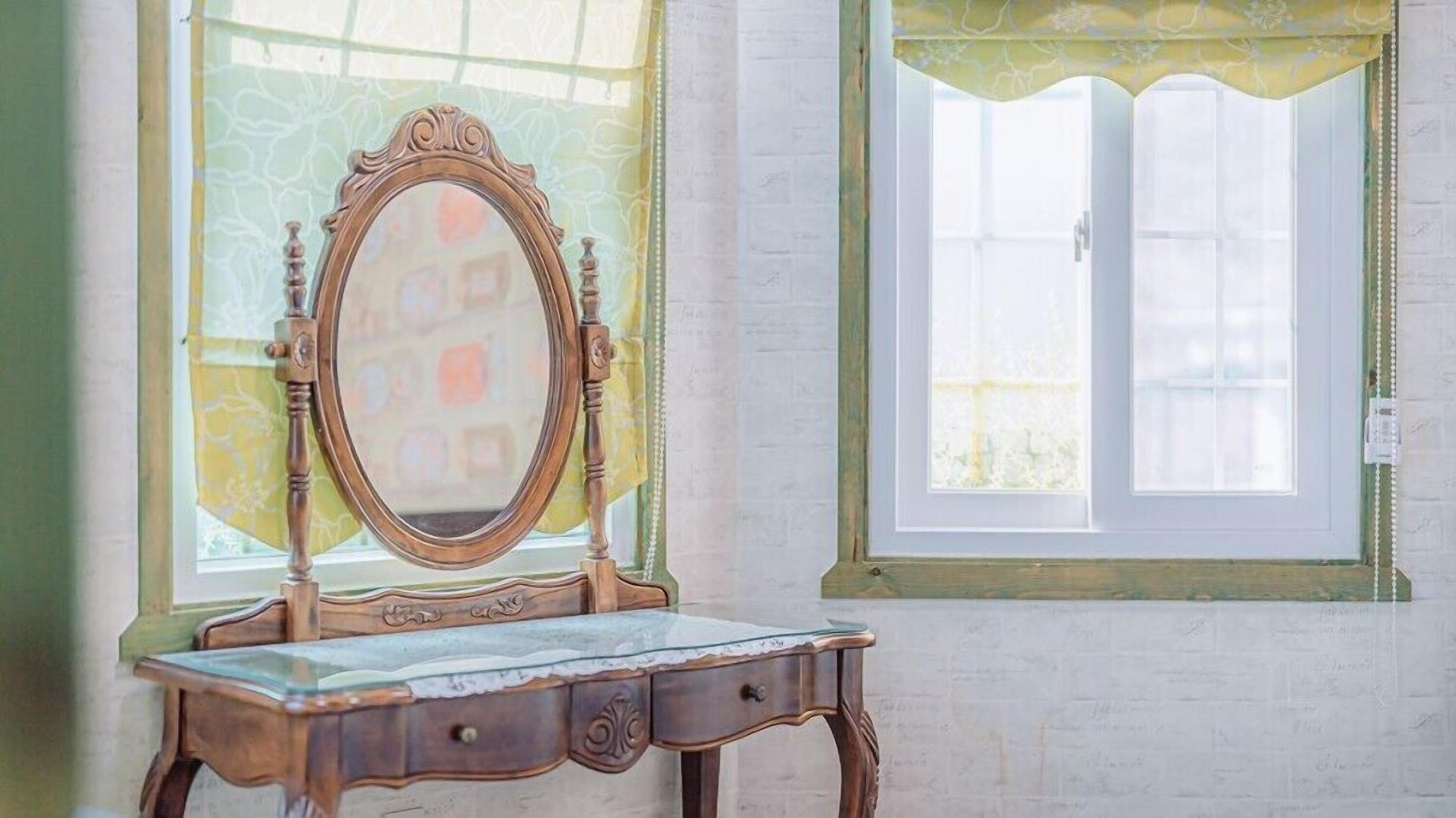 A vintage vanity with a mirror, a small drawer, and a glass top.