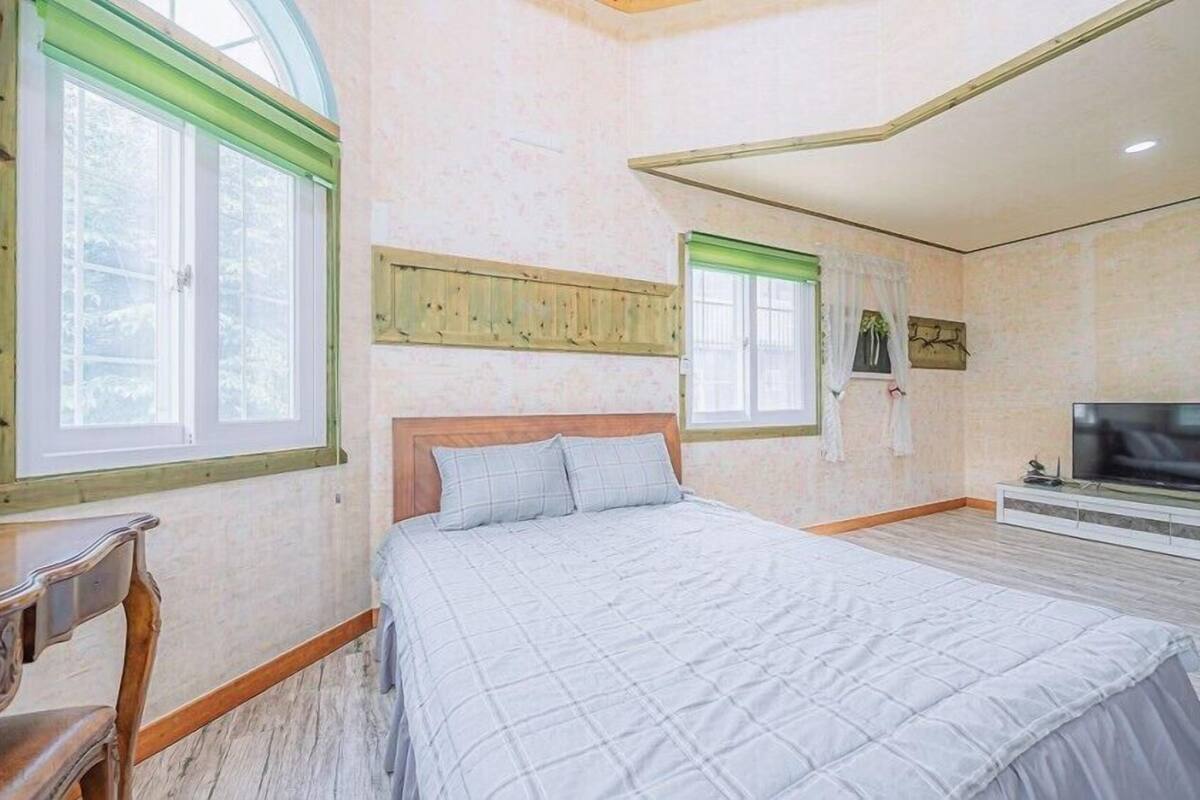 Un dormitorio con una cama grande, televisión y cabecero de madera.