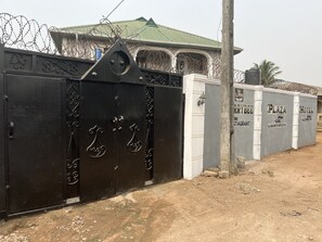 Une propriétéClose, dotée d’un portail en métal, d’un bâtiment surmonté d’un toit végétalisé et d’une enseigne indiquant « Plaza Bar & Restaurant ».