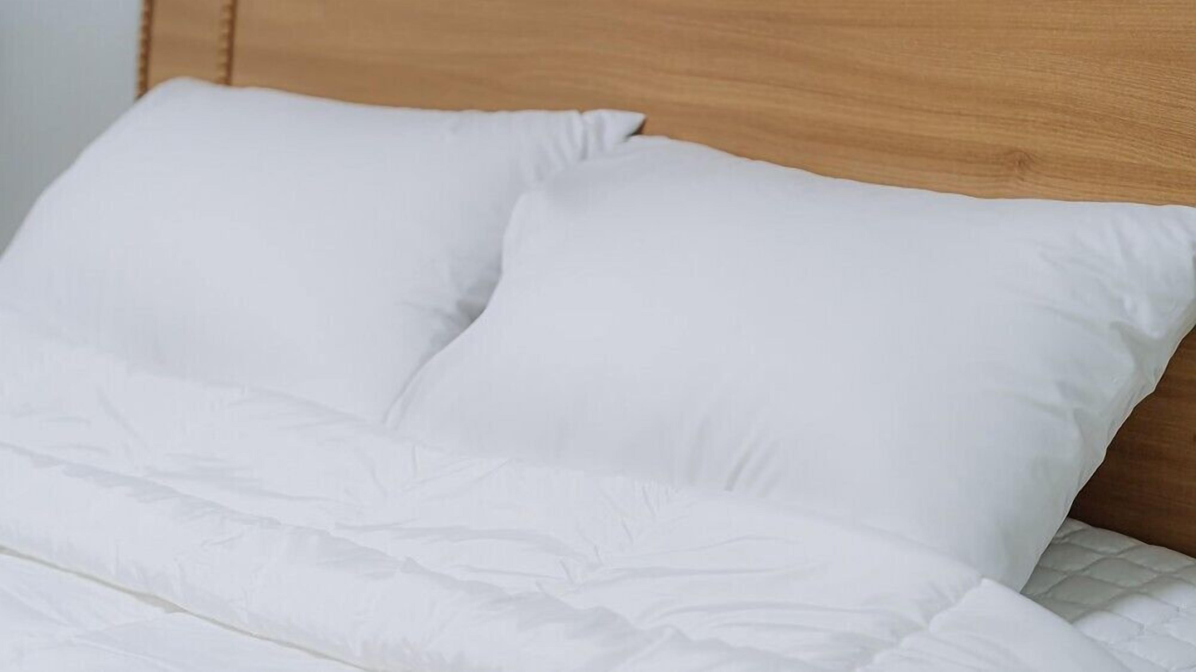 A bed with white bedding and a wooden headboard.