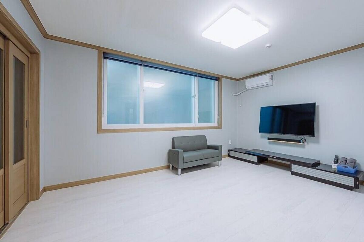 Una sala de estar moderna con un ventanal grande, un sofá gris, un televisor de pantalla plana y un mueble empotrado para entretenimiento.