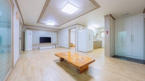 Una habitación amplia con una mesa de madera, un televisor de pantalla plana montado en la pared y una zona de kitchenette.