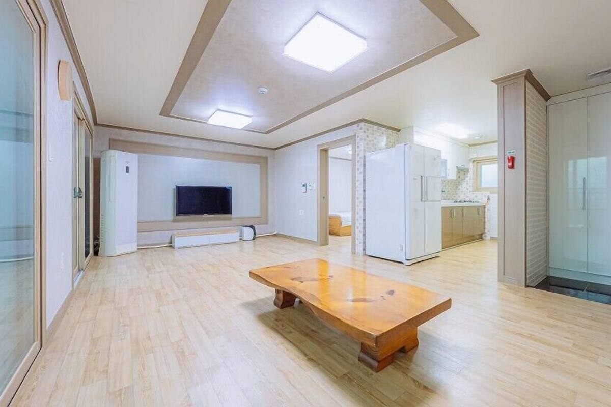 Una habitación amplia con una mesa de madera, un televisor de pantalla plana montado en la pared y una zona de kitchenette.
