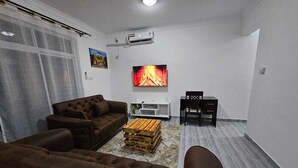 A living room with brown sofas, a wooden coffee table, and a TV displaying a fireplace.