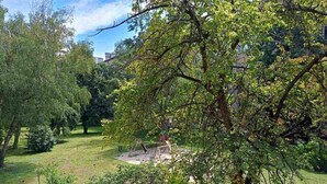 Ein üppiger Garten mit Schaukel und kleinem Teich.