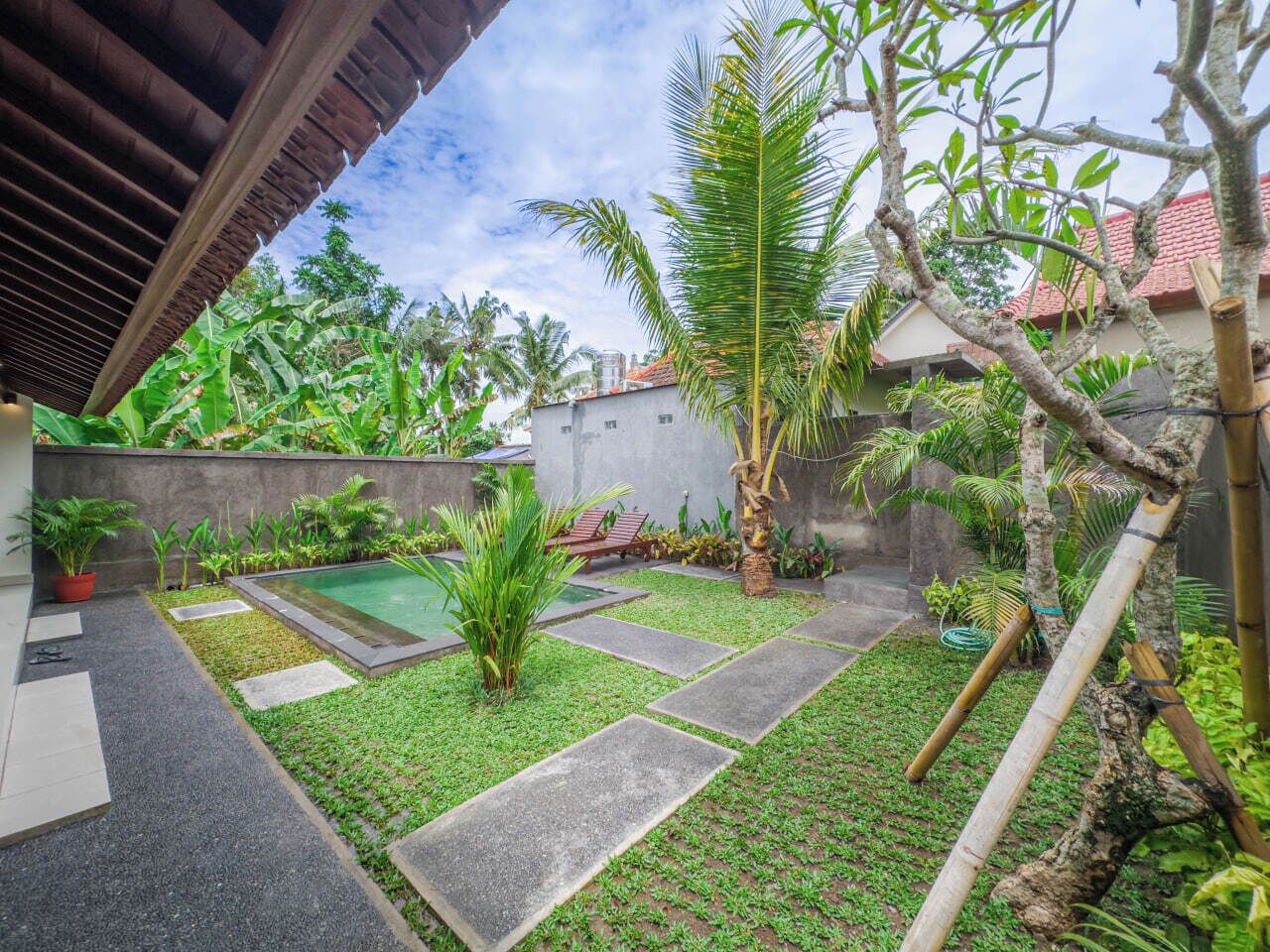 A well-maintained garden with a swimming pool, stone pathways, and various tropical plants.