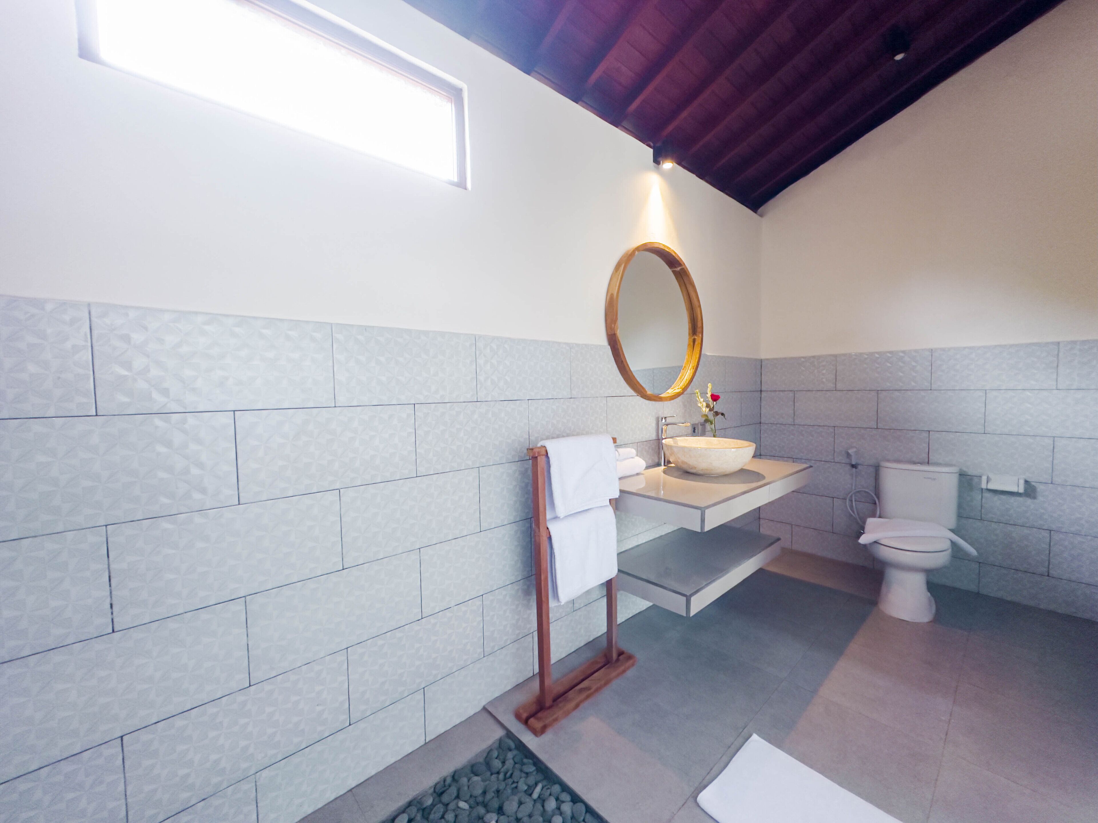 A modern bathroom with a large mirror, a sink, and a toilet.