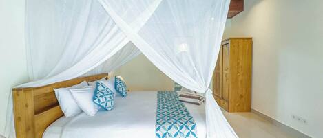 A bed with a wooden frame, white bedding, and a blue patterned throw.