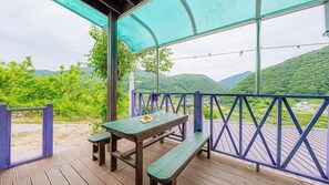 Una terraza de madera con una mesa de picnic y bancos, con vistas a un paisaje montañoso.