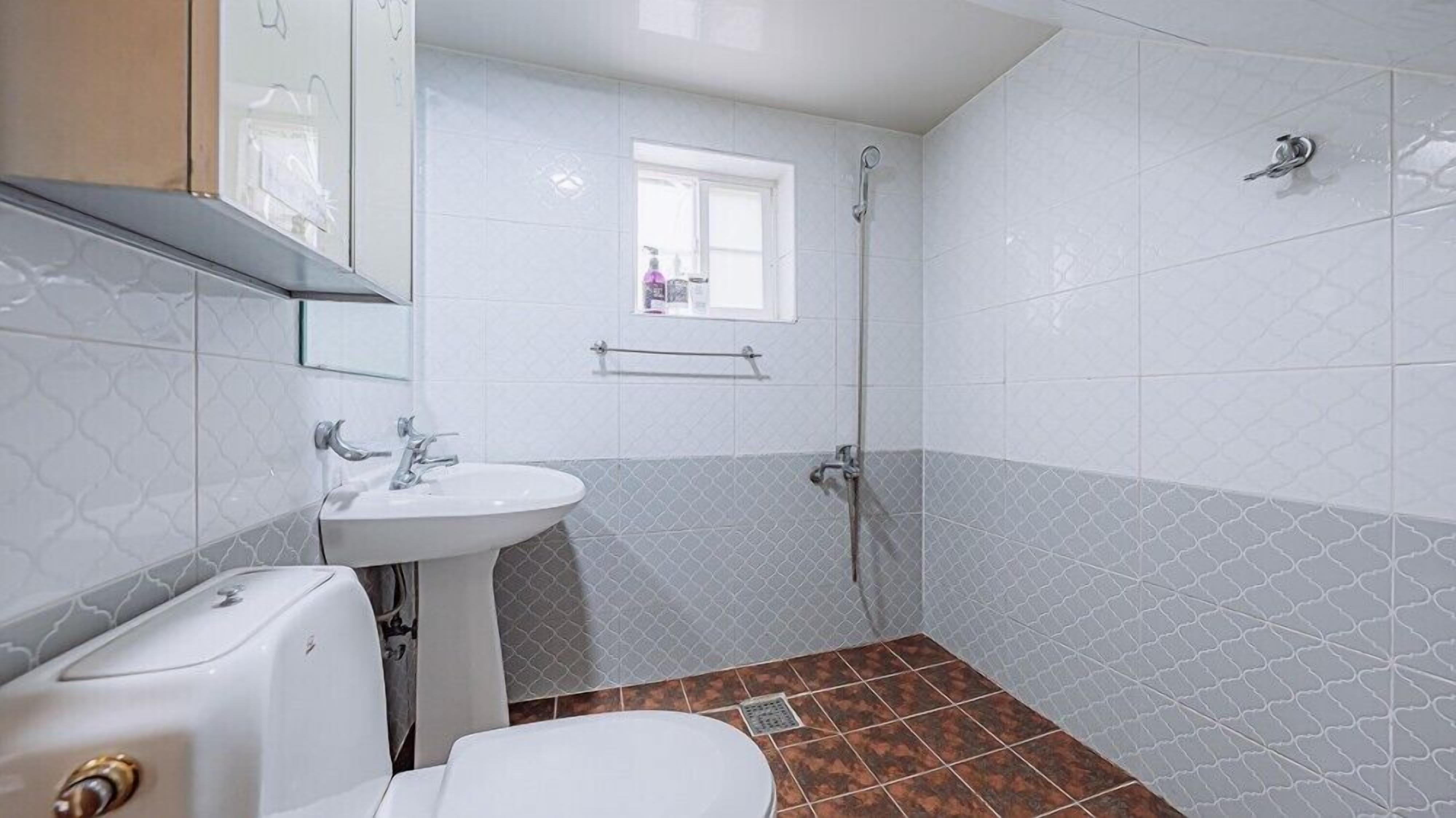 A bathroom with a white sink, a toilet, and a shower.