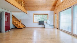 Amplia habitación con escalera de madera, un ventanal grande y un cerramiento de vidrio corredera.