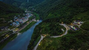 Vista aérea de un pueblo a orillas de un río, con casas a lo largo de la ribera, un puente y un pequeño embarcadero.