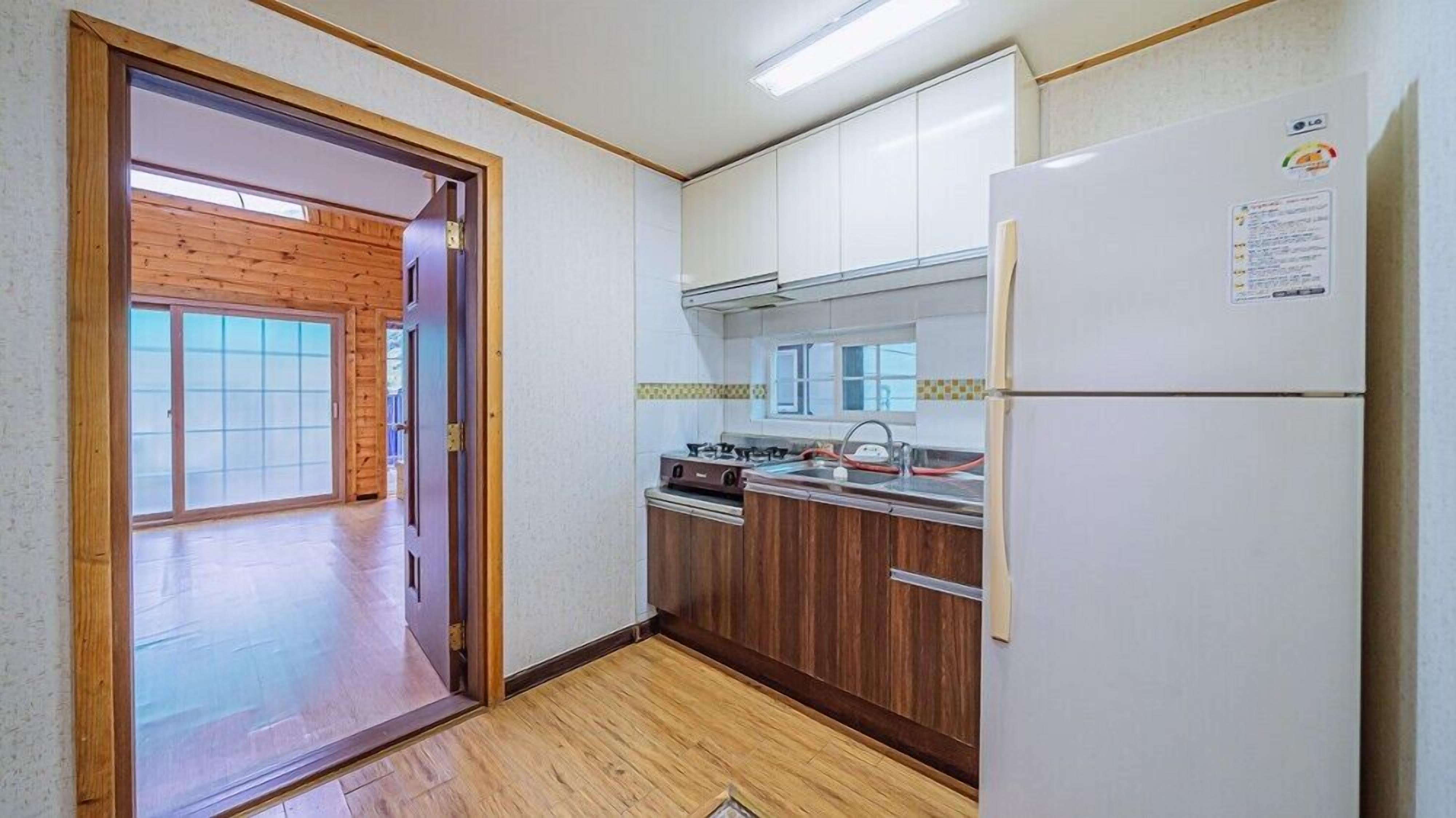 A compact kitchen with wooden cabinets, a gas stove, and a white refrigerator.