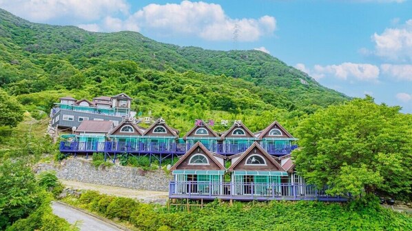 Un hotel en una ladera con varias edificaciones, balcones y un muro de piedra de contención.
