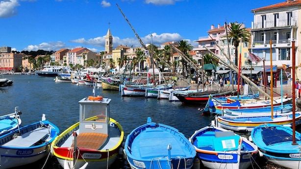 A marina with various boats docked, a church in the background, and buildings along the waterfront. - Très Beau T2 Neuf, Calme, Terrasse, au Cœur de Sanary + box Fermé en Sous-sol (Sanary-sur-Mer)