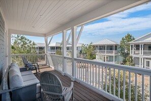 A covered outdoor area with a white railing, a sofa, and a table.