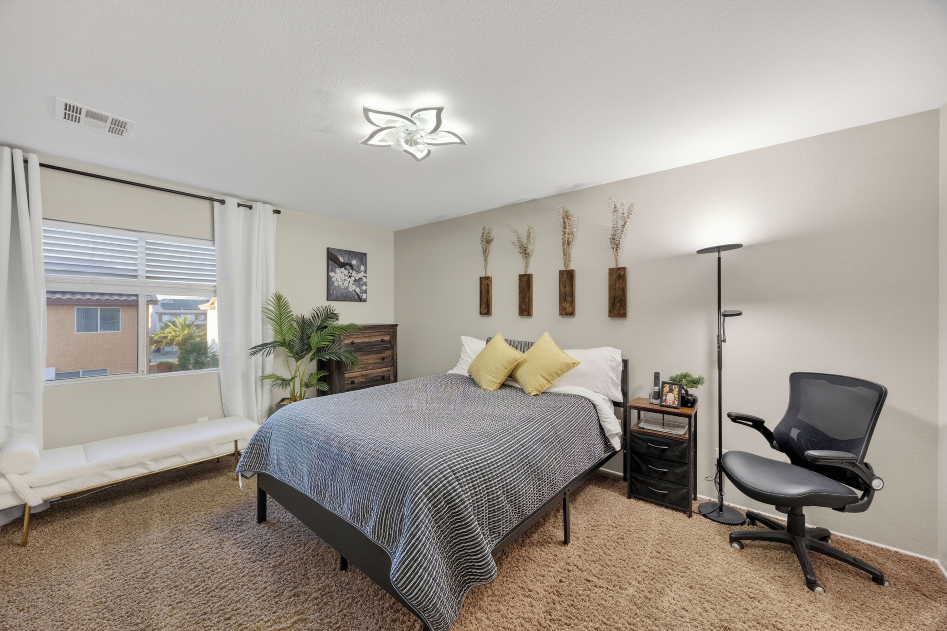 Ein Schlafzimmer mit Bett, Nachttisch, Lampe, Sessel, Fenster und dekorativen Wandelementen.
