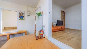 Une pièce comprenant une table en bois, un banc, un extincteur, un téléviseur et un meuble.