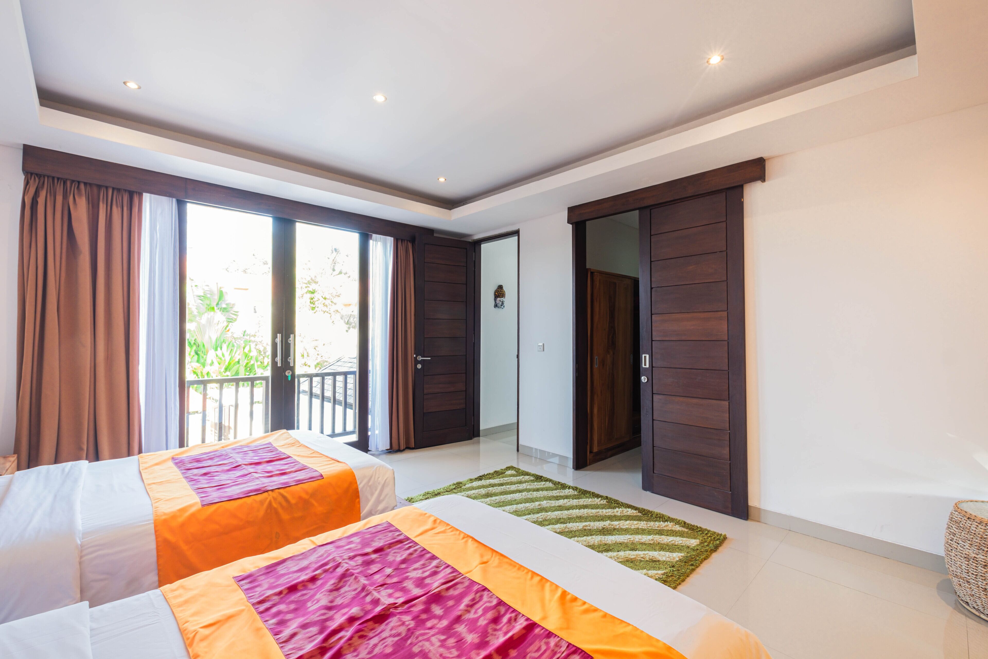 Habitación de hotel con dos camas, un balcón y una puerta corredera a un patio.