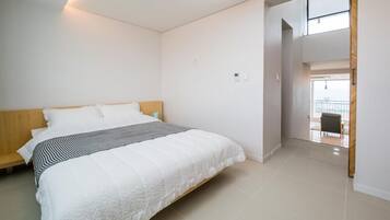 Un dormitorio con una cama, cabecero de madera, pared blanca y puerta que da a un balcón.