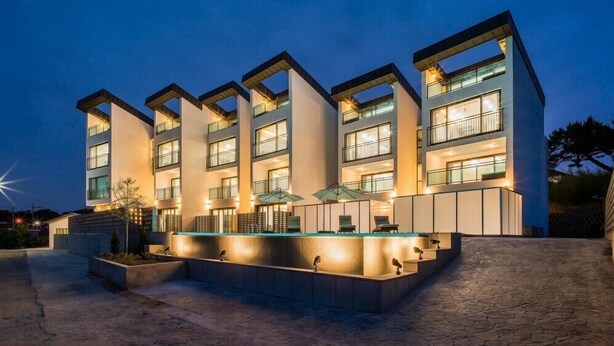 Un hotel moderno con varios pisos, mobiliario exterior y una piscina.