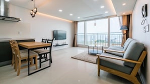 Una sala moderna con comedor, sofá, televisor y balcón con vistas.