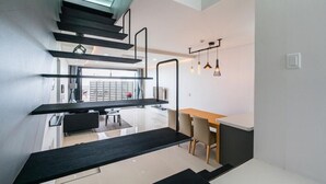 Un interior moderno con una escalera que conduce a un comedor, una cocina y vistas a través de un ventanal.