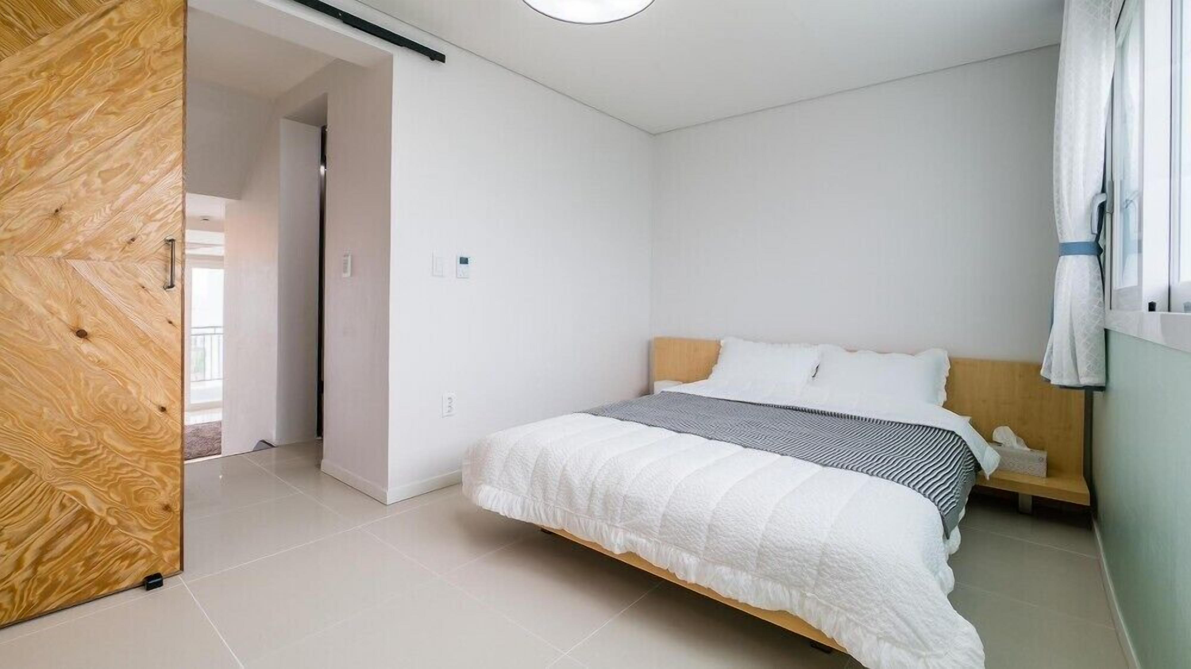 Un dormitorio con cama, un armario de madera y una ventana con cortinas.