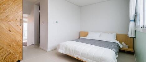 Une chambre à coucher avec un lit, une armoire en bois et une fenêtre avec des rideaux.