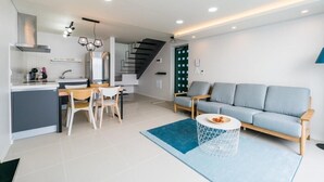Una cocina moderna con comedor, sofá y una escalera que sube a otro nivel.