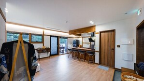 A modern kitchen with a bar area, wooden flooring, and a view through the glass door. - GurYong RyoKan (Pohang)